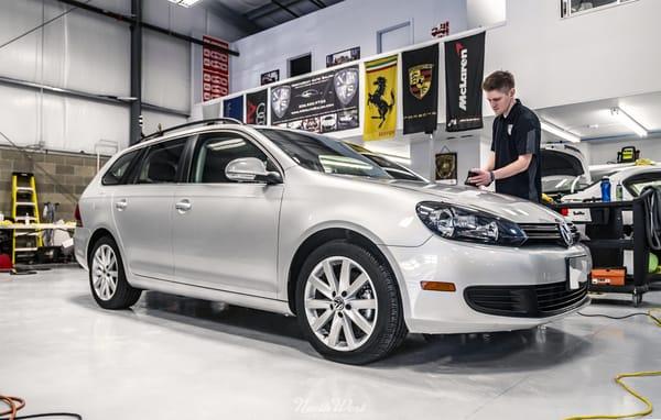 Reconditioning Specialist Josh works away on a VW Jetta wagon that's due for paint correction.