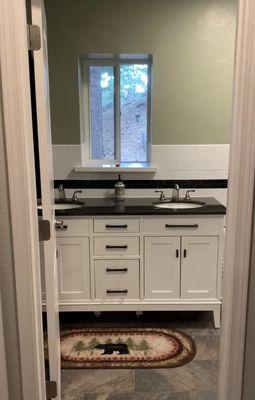 This is a full bathroom with shower over tub, stone floor and excellent tile work.