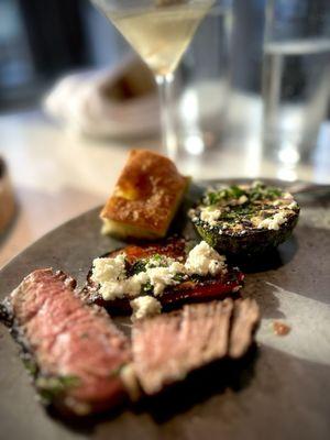 Close up of the steak, along with a vodka martini with stuffed olives and vegetables