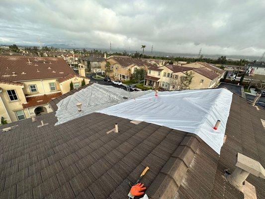 Emergency tarping to cover roof leak from recent heavy rains.