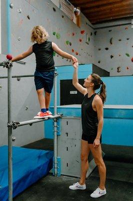 Coach Paisley helping a balance portion of an obstacle course for more advanced parkour students.