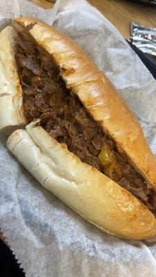 Cheesesteak with sauce, onions, banana peppers. Delicious