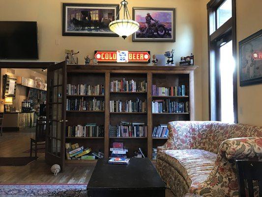 Large room with fireplace, couches and many books.