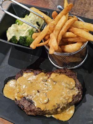 The Sirloin Diane with a basket of Seasoned Fries and a square black bowl of Broccoli with melted cheese on top.