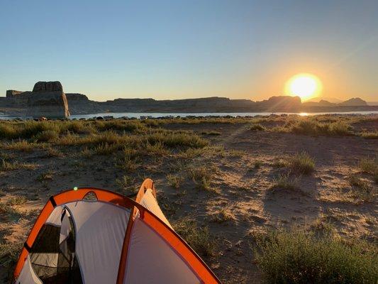 sun rising over water and tent