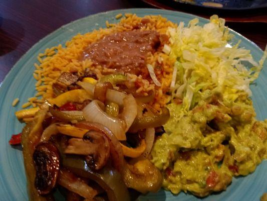 Vegetable fajitas with rice, salsa, shredded lettuce and guacamole