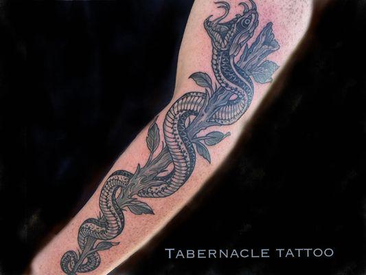 Black and grey snake tattoo on forearm