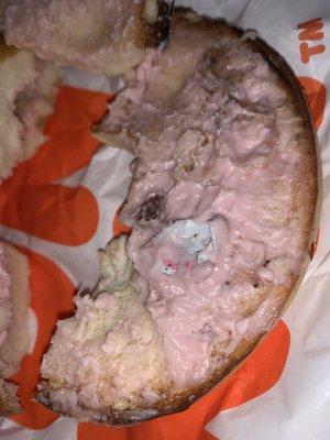 Plain bagel with strawberry cream cheese and part of the lid