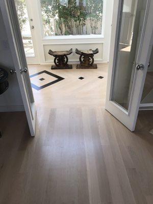 Whitewashed oak flooring with dark stained walnut inlays.