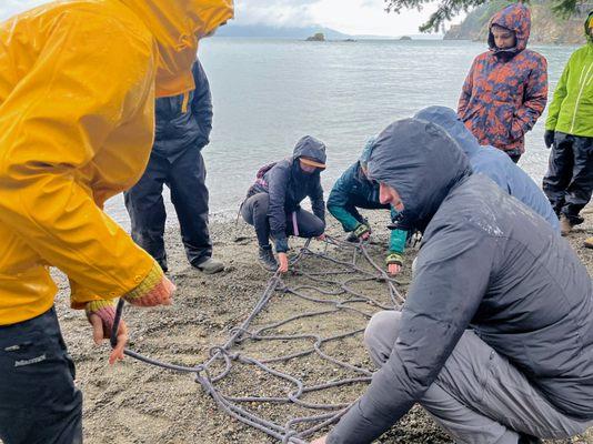 Learning how to make an innovative rope litter on the beach.