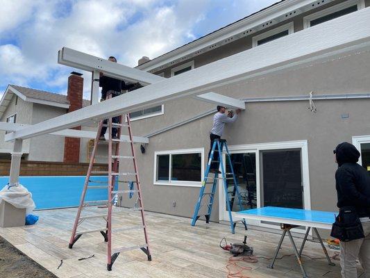 Installation of the ridge beam and ultimately the roof panels (see panel with blue protective film).