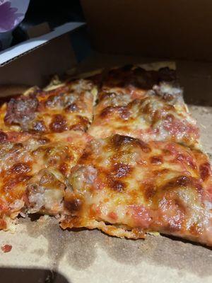 Thin crust sausage pizza without extra cheese.