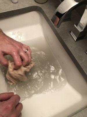 Hand washing my wife's previously pink T-shirt in sink after wash and fold service from Youme.  Water is FILTHY