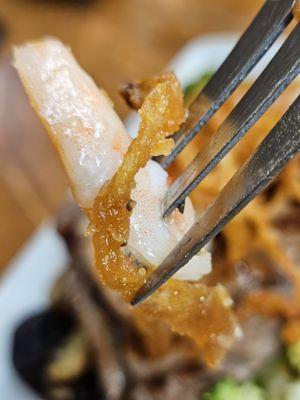 A piece of shrimp and onion string on a fork.