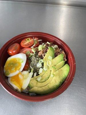 Breakfast bowl: jasmine rice, bacon, avocado, soft poached egg, tomatoes, and sesame verde, garnished with green onion.