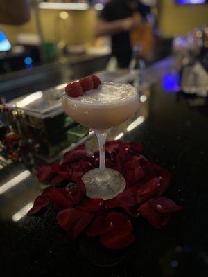 Cocktail with fresh raspberry and rose petals