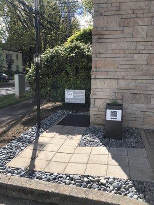 Look for the gray planter and river rocks on the exterior corner of the building.