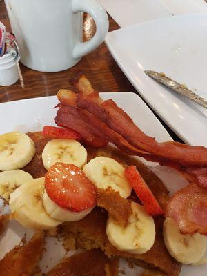 Pancakes with strawberries, bananas and a side of bacon.