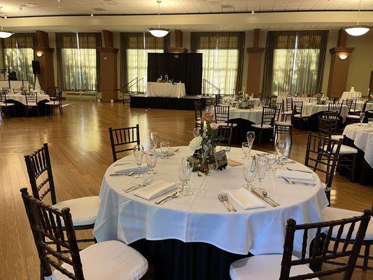 A display of the Young Main Lounge in Illinois Wesleyan University. Shows a more elegant white wedding set up for a couple of round tables.