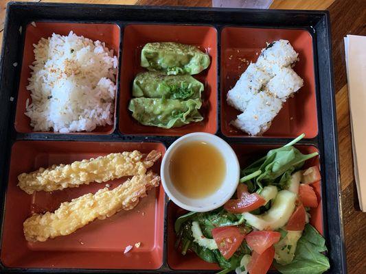 Bento box with rice, vegetable gyoza, California roll, tempura shrimp and salad.