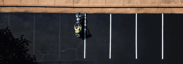 Blue Curb LLC Contractor Lining Up the Parking Space Lines in a Freshly Paved Parking Lot