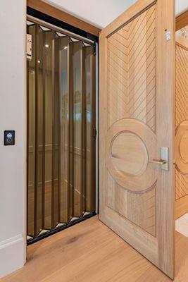 Bronze tone acrylic panels on a home elevator accordion gate.