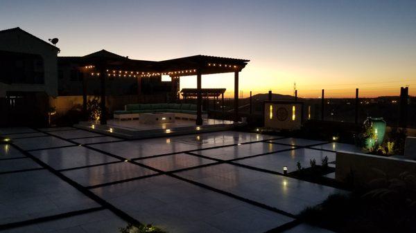 Tiled patio with artificial turf insets. Raised patio & arbor. Custom water feature with back lit glass panels.