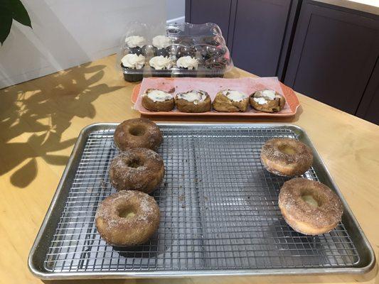 Apple cider donuts and cinnamon rolls. Far back are chocolate cupcakes