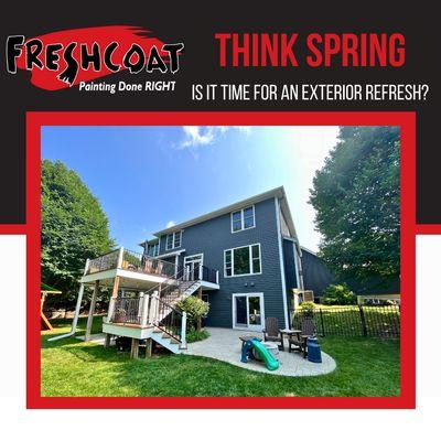 Center image of freshly painted home with slate blue siding and white trim with large deck in summertime.