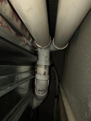 Poorly primed/glued PVC pipe connection that leaks water/ exhaust fumes. Water is dripping from pipe fitting.