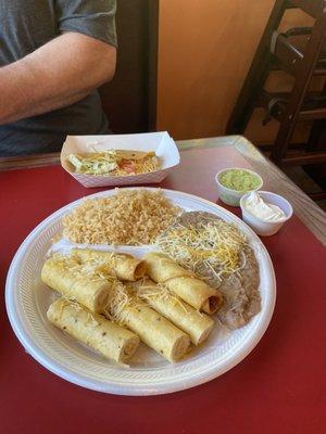 Chicken flautas  with beans and rice, ground beef taco on crunchy corn tortilla with guacamole and sour cream