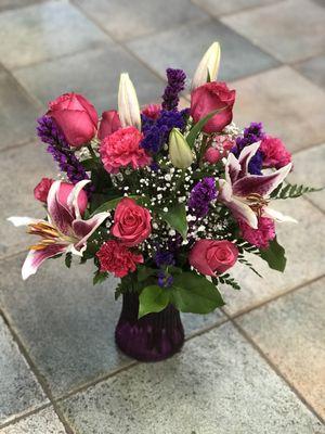 Stargazer Lilies mix with flowers in a purple base.