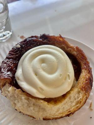 Cinnamon bun topped with whipped cream cheese