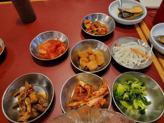 Assorted sisdes - potatoes (sweet), kimches (radish, cucumber, cabbage, eggplant), pickled radish, bok choy