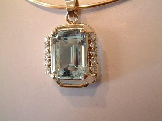 21 ct Emerald Cut Aquamarine set in 14K Gold with 10- .10 ct Round Brilliant cut Diamonds.