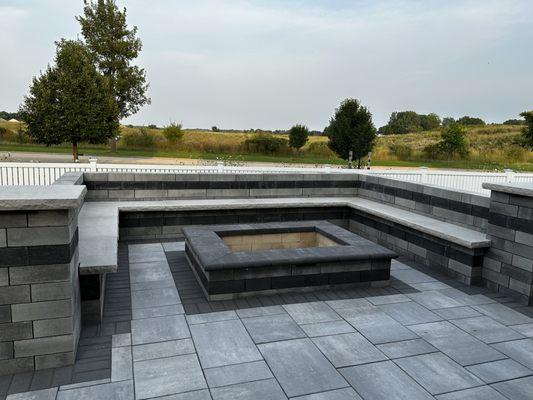 Modern patio with a sleek firewood fire pit and bench seat walls.