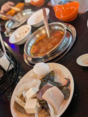 Tomato broth, plate of uncooked seafood and tofu about to be tossed in.  Remember to drink their broths too, not salty.