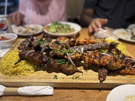 Medium mixed grill platter served with multiple different sauces on the side, a salad, and rice.