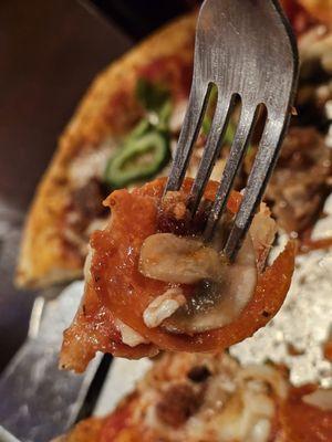 Close-up of a fork holding a piece of the Pizza Suprema.