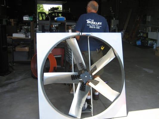 Joe Birkley getting ready to install a 4' exhaust fan in a warehouse.