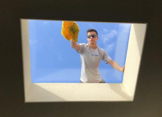 Kristian cleaning the new large flat glass skylight.  Skylight replacement specialists.