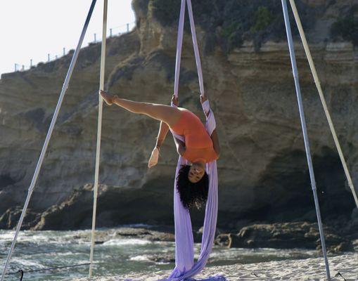 Lovely peach colored leotard against a beach backdrop and lavender Silks.