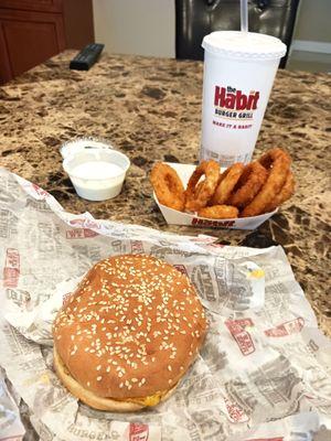 Char burger with onion rings.