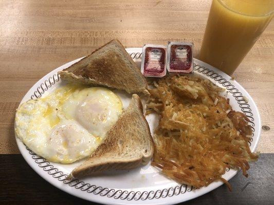 Two eggs medium, hash browns scattered, white toast, strawberry jelly and orange juice