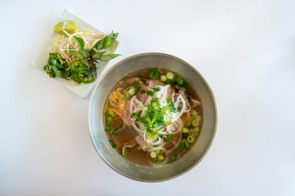 Tradition Vietnamese beef noodle soup featuring rare beef, beef briskets and traditional veggies.