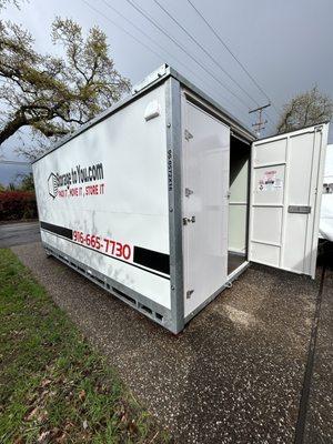 Side view of the container on a driveway with one door open.