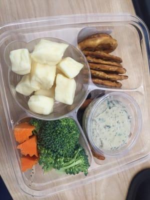 Protein snack pack featuring beecher's cheddar cheese, veggies and hummus, and pretzel chips.