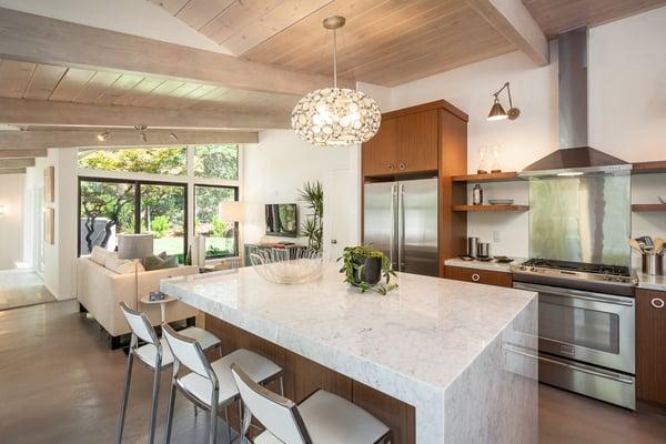 Stainless appliances and a stunning light fixture over Carrara marble island. Who wouldn't want to cook a meal in here?!