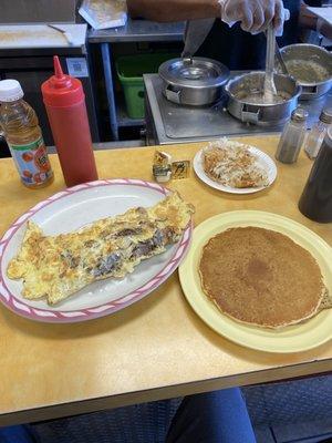 Steak Omelette, a single pancake, and shredded hash browns with an apple juice.