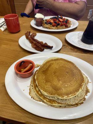 Buttermilk Pancakes in foreground, Waffle w/ Strawberries & Blueberries in background.